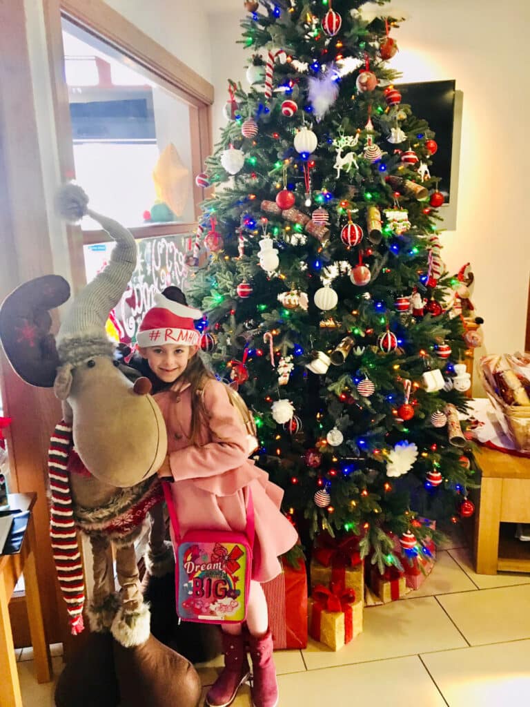 Little girl with reindeer beside Christmas tree